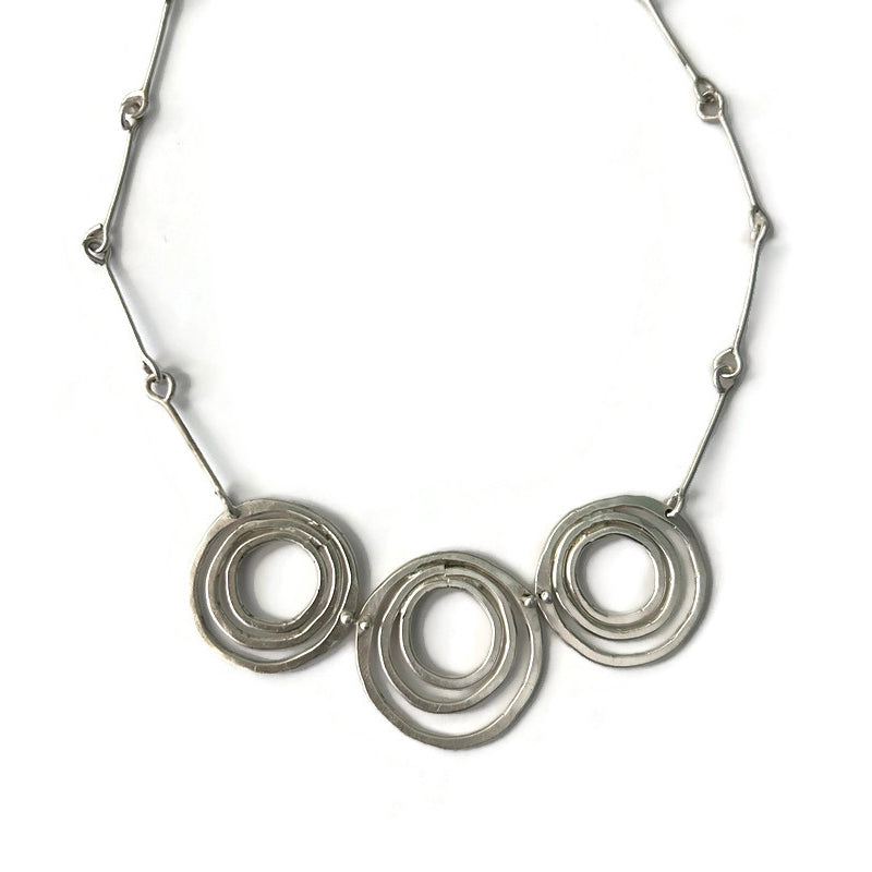 Silver necklace with three interlocking rings on a white background