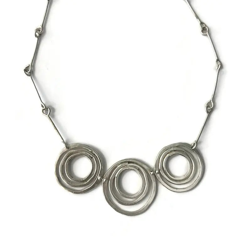 Silver necklace with three interlocking rings on a white background