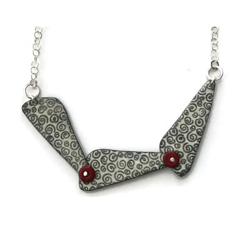 Necklace with a geometric pendant featuring a gray pattern and red accents on a white background