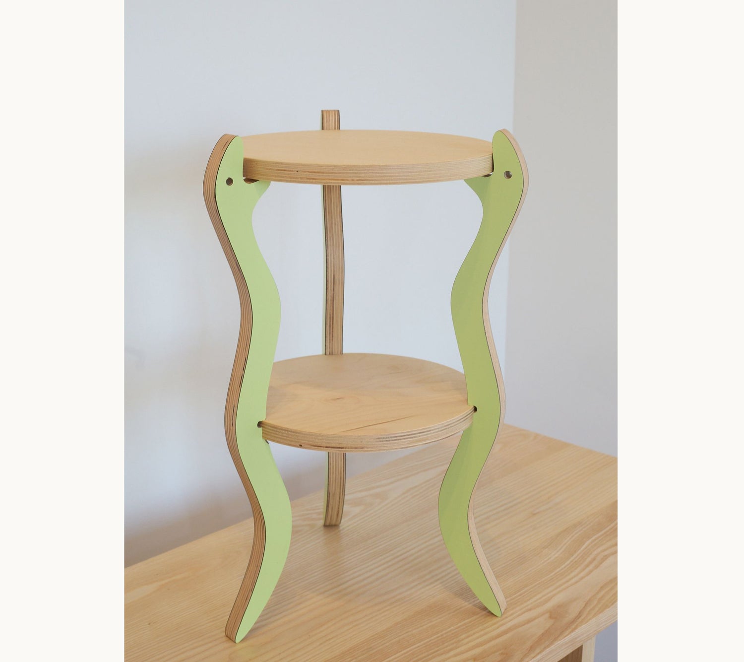 Wooden side table or plant stand with green legs on a wooden surface
