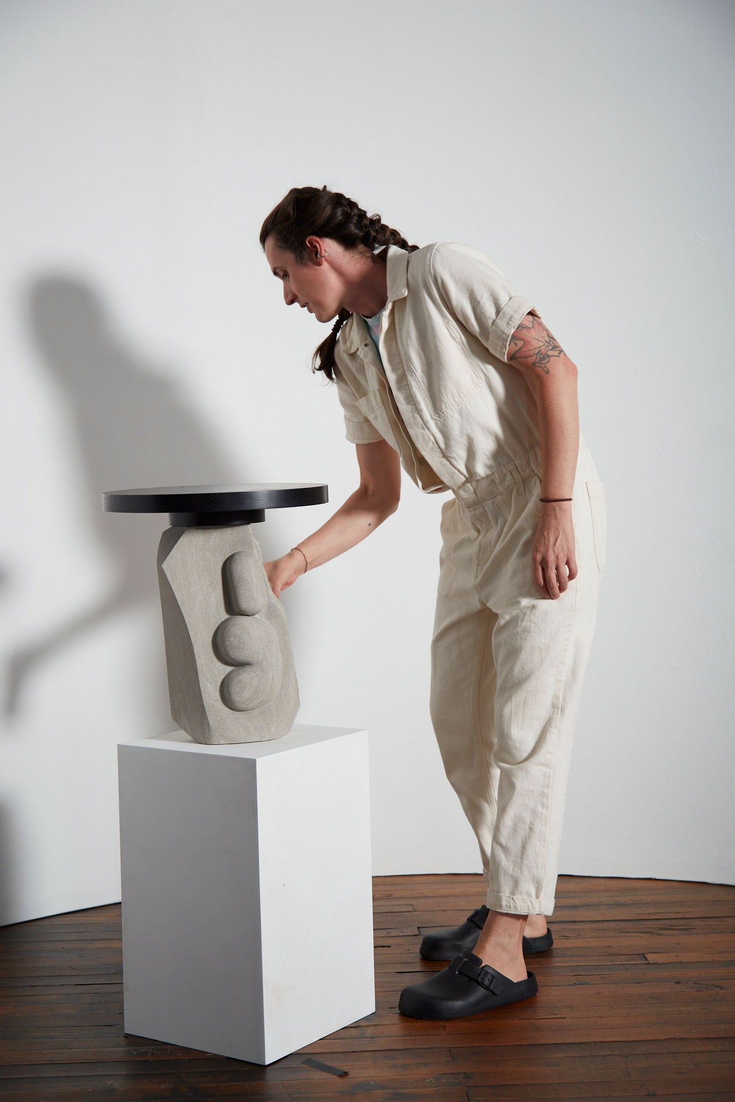 Person interacting with a modern stool against a white wall