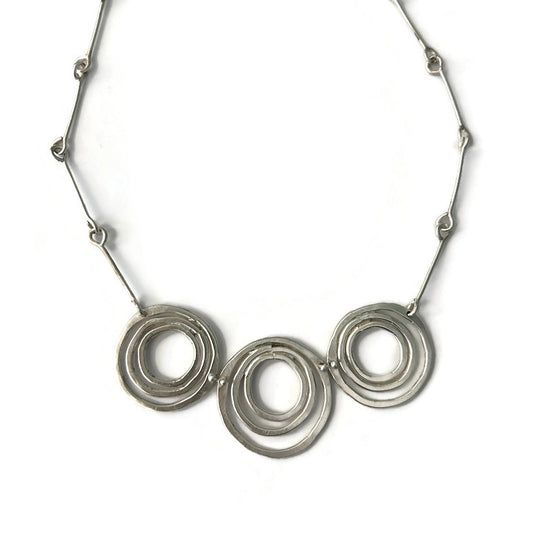 Silver necklace with three interlocking rings on a white background