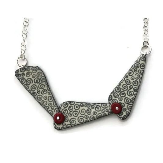 Necklace with a geometric pendant featuring a gray pattern and red accents on a white background