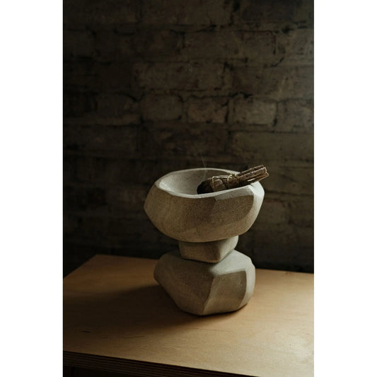 Stone burn bowl on a wooden surface with a dark stone wall background
