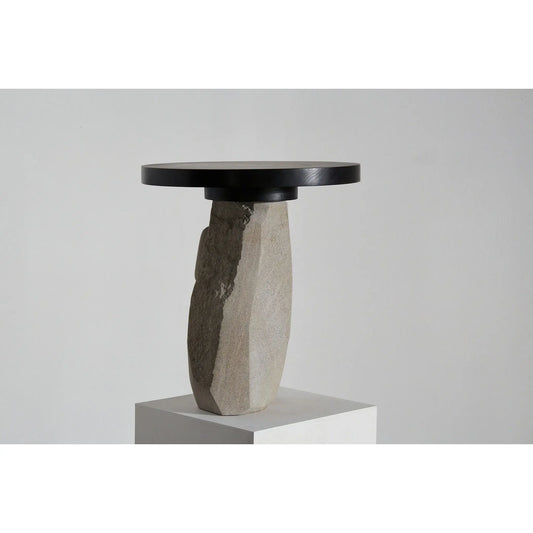 Side table with black round top and stone base on a grey background